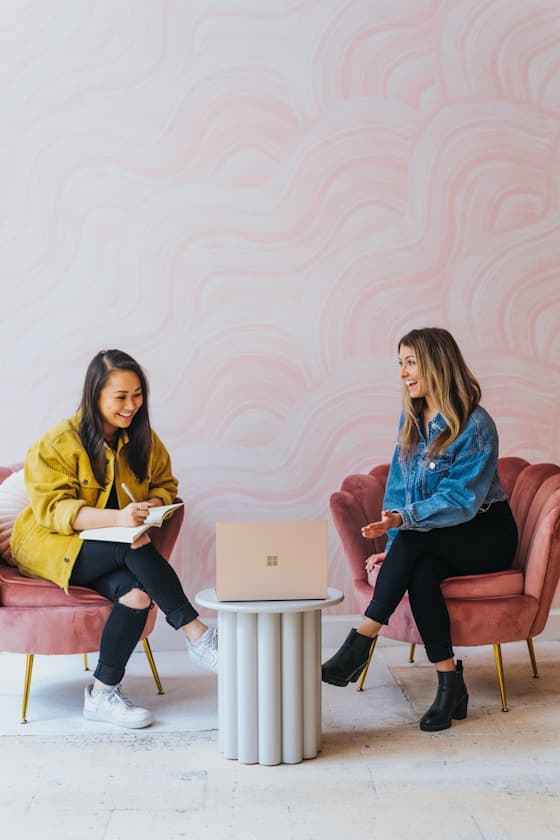 Two people sitting on pink chairs
